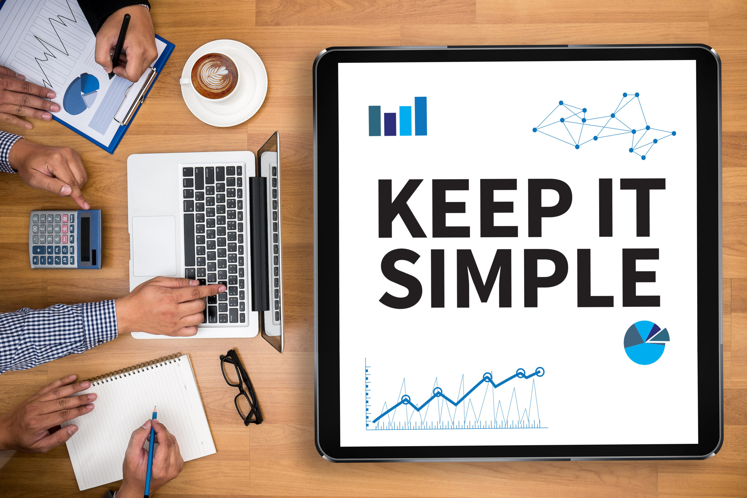 Screen displaying 'Keep it simple' with graphs and charts, surrounded by hands of three people using a calculator, notebook, and computer in a decision-making meeting for military retirees.